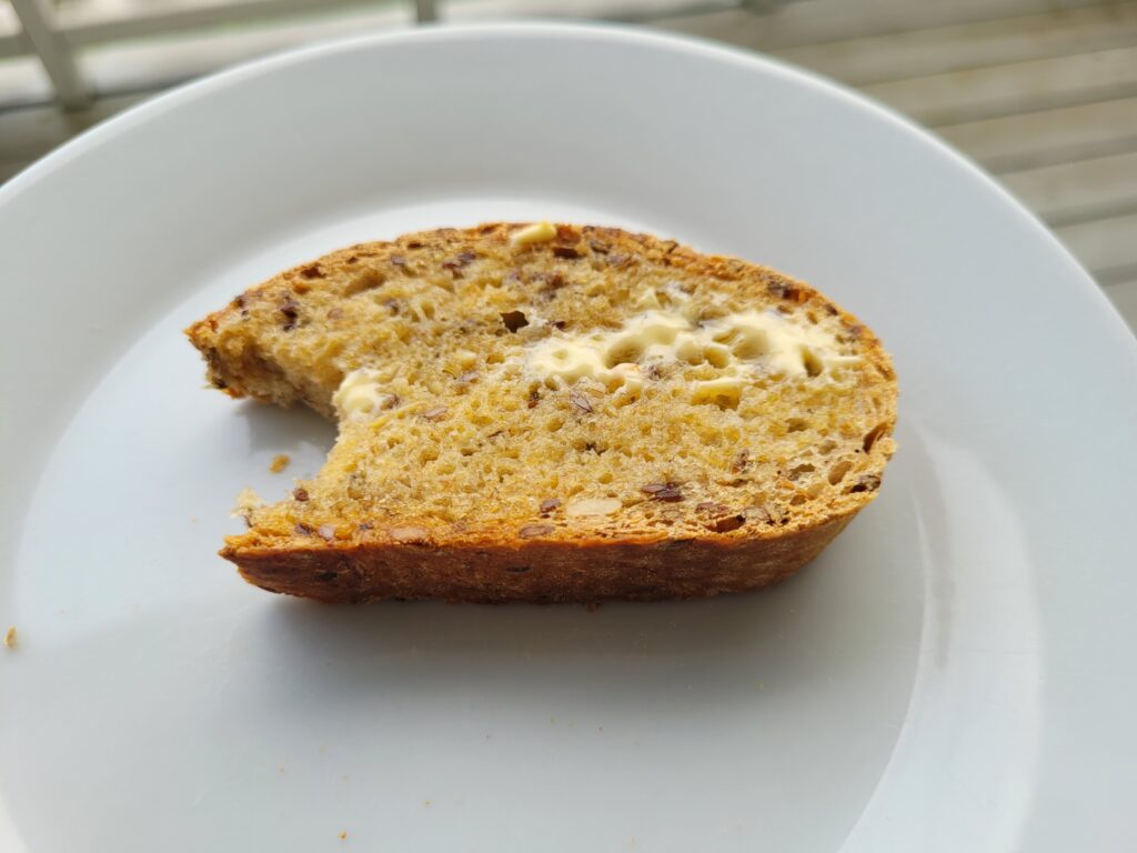 Ei skive brød med smør som har smeltet ligger på en hvit asjett. Det er tatt en bit av skiva.